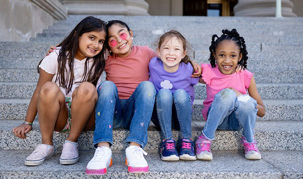 Six Girl Scouts of various ages sitting on a couch together